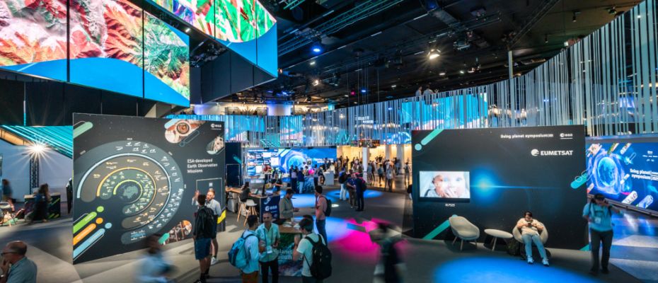 Copyright: ESA/JMai
Ein Ausstellungsraum voller Besucher:innen und mit vielen bunten Bildern und Animationen zu Weltraumthemen